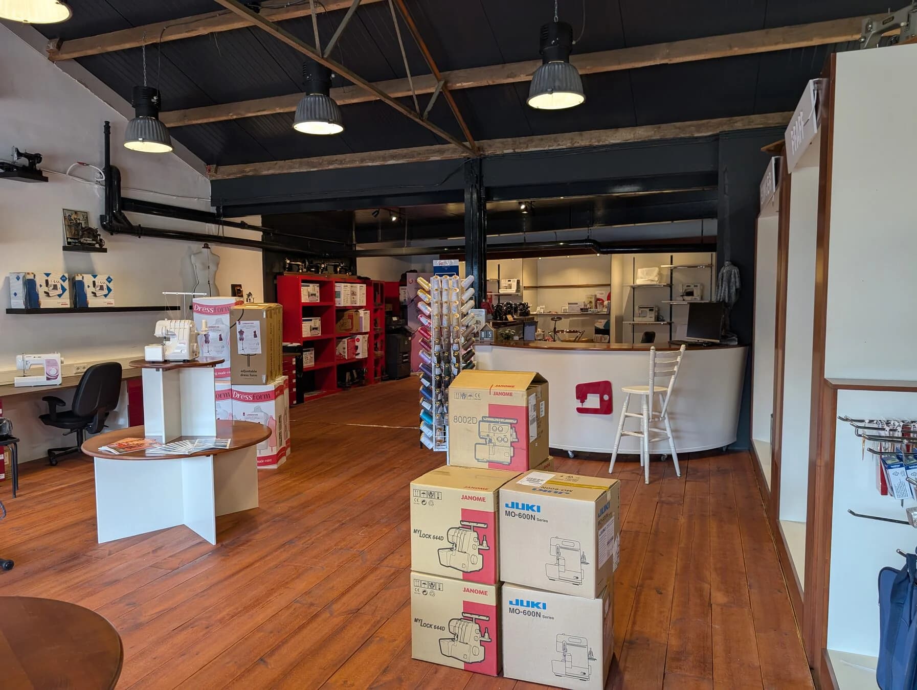 Overzicht van de Matri-showroom met naai- en lockmachines, garen en verpakte paspoppen