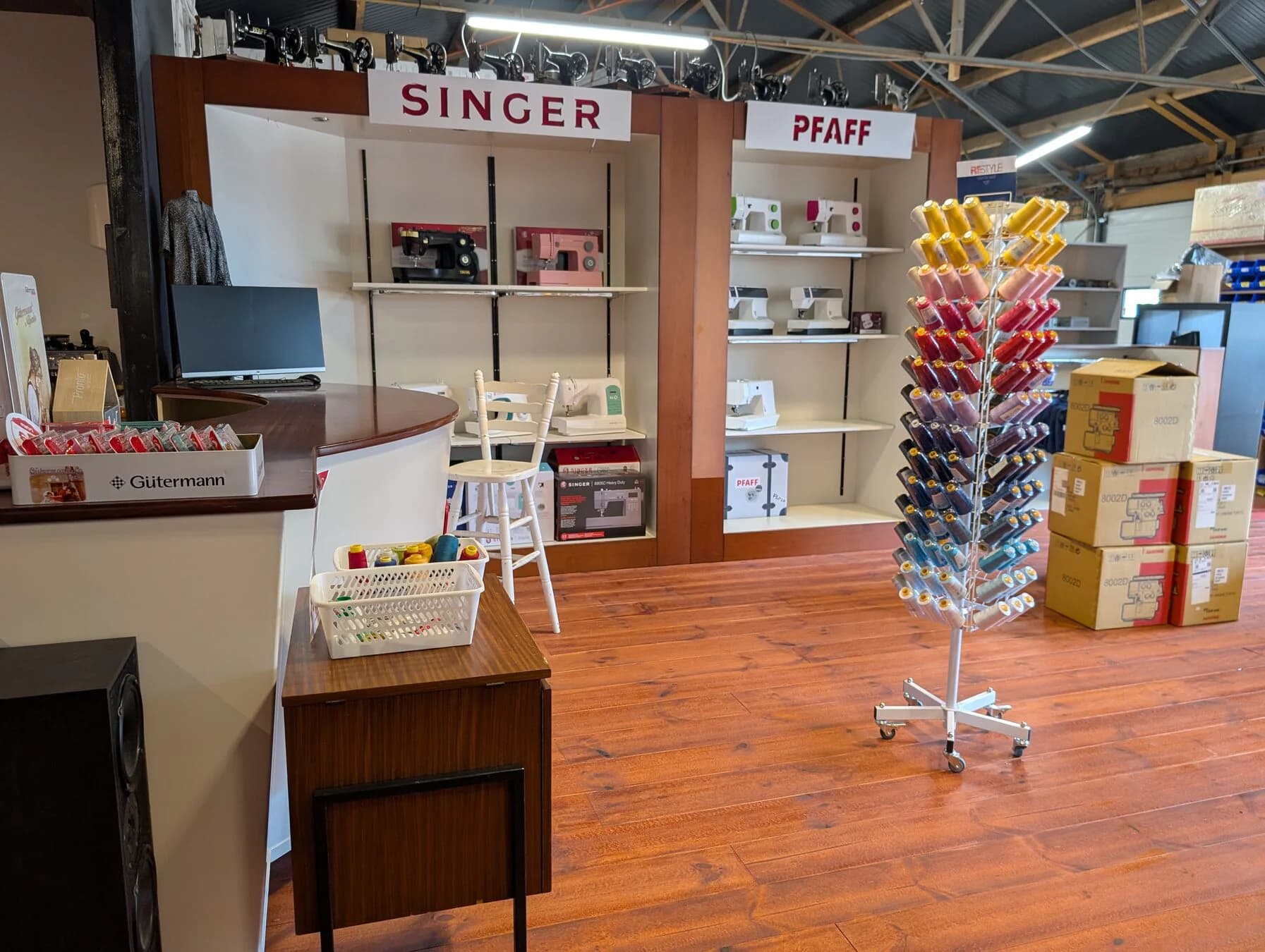 Singer- en Pfaff-naaimachines met een kleurrijk garenrek in de showroom van Matri in Eefde